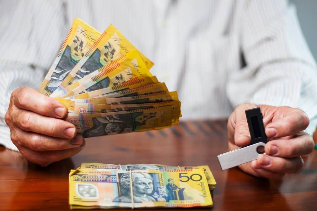 Man`s hands are holding australian dollars and nano wallet