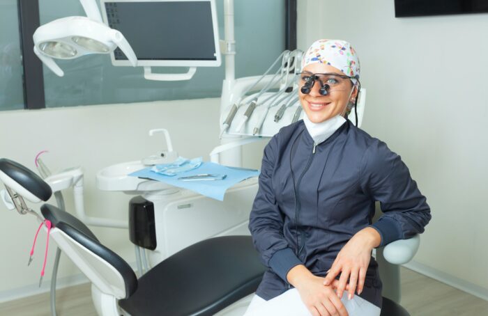 Beautiful female dentist sitting near the dental chair