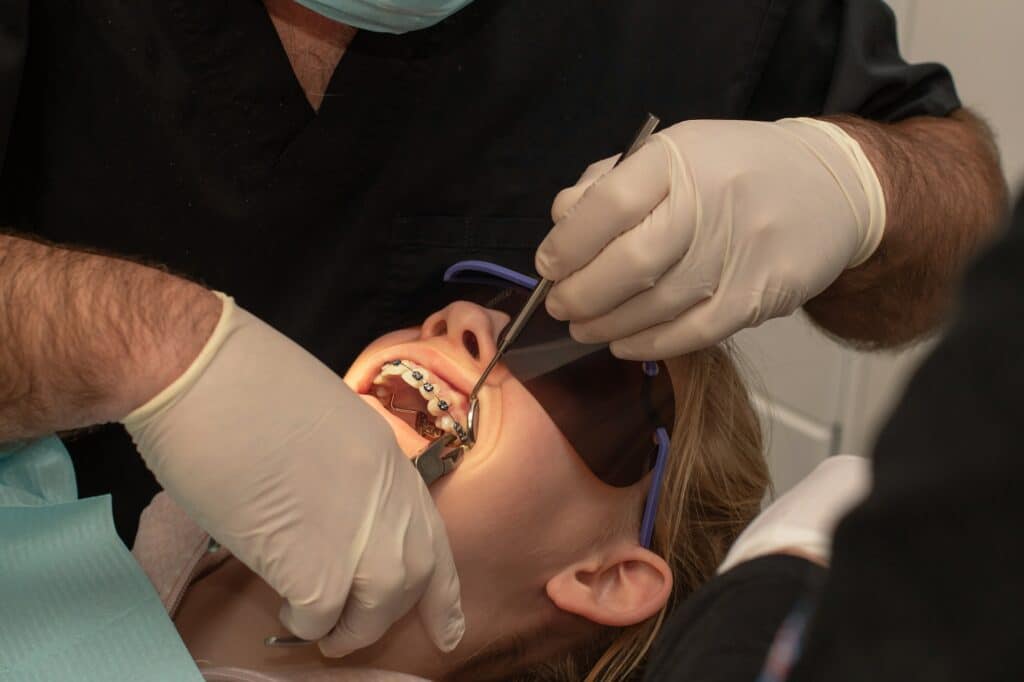Orthodontist fixing taking off metal braces. Orthodontic treatment. Removing metal braces