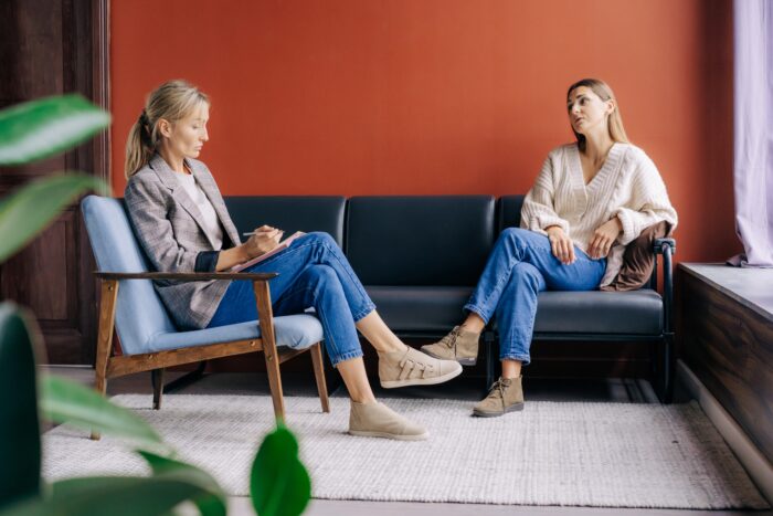 A female psychotherapist attentively listens and counseling a young woman talking about problems.