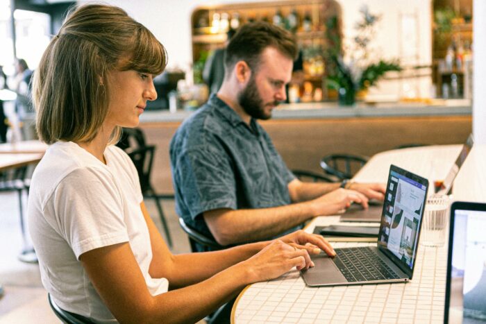 Man and a woman sitting at a table with laptops