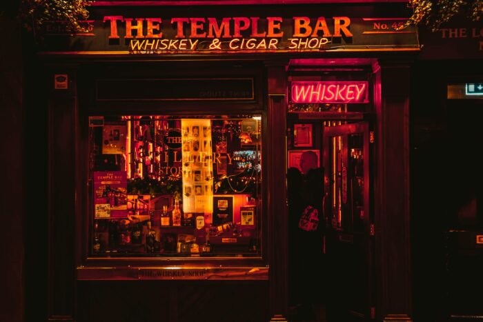 Man standing outside of a whiskey shop at night