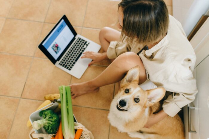 Woman sitting on the floor with a dog and a laptop