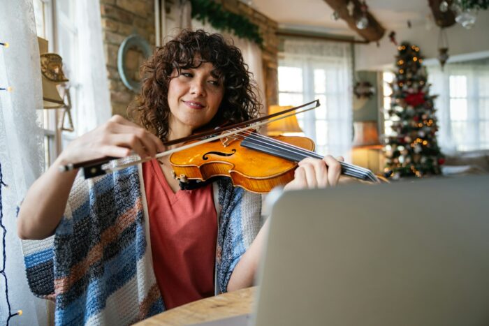 Woman music teacher teaching how to play a song the violin online during a video call