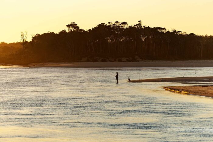 Man fishing on a river at sunset
