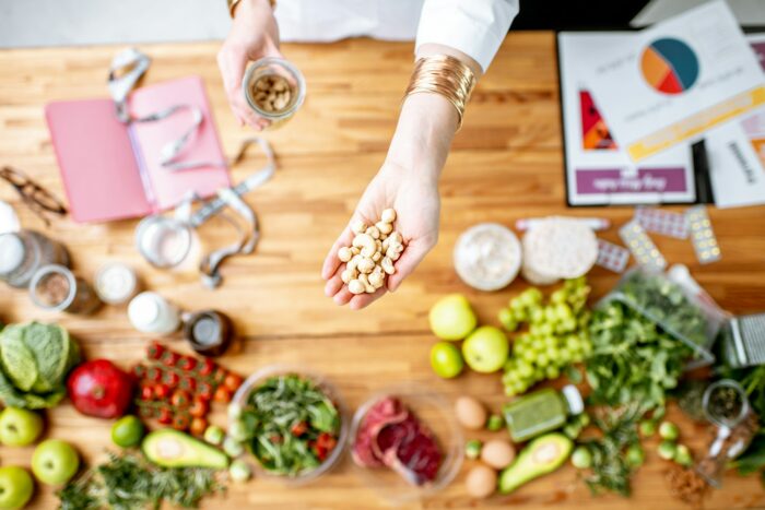 Dietitian holding nuts above the table full of healthy food