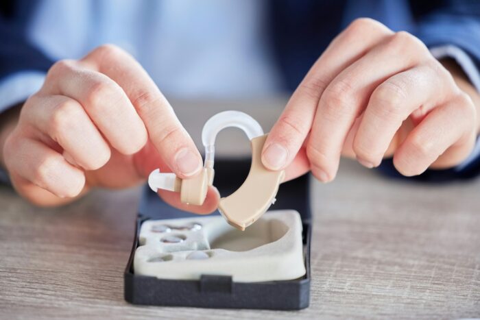 Hearing aid, disability help tool and hands with hospital, wellness and medical audio innovation. L
