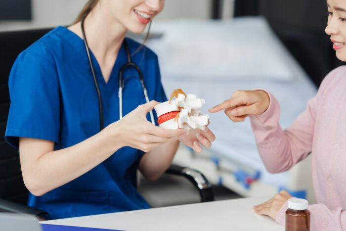 Caucasian female doctor explain to asian female patient using Human Anatomical Lumbar Disc
