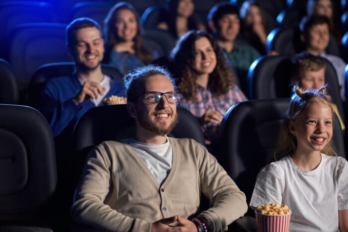 Young man with younger sister in movie theater