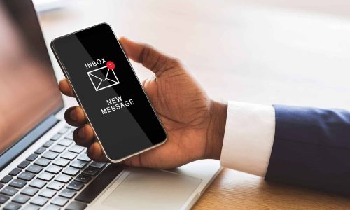 Black Businessman Holding Smartphone Reading E-Mail Message In Office Black Businessman Holding Smartphone Reading E-Mail Message In Office