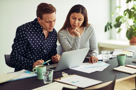 Focused coworkers using a laptop together at an office desk