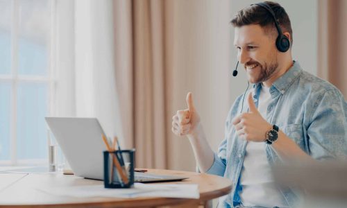 Satisfied bearded male model attends online training from home uses headset Satisfied bearded male model attends online training from home uses headset